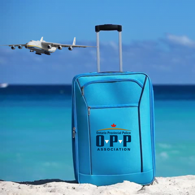 OPP suitcase in the sand with an airplane and the ocean in the background